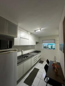 cocina con armarios blancos, mesa y ventana en Apartamendo Marina Clube, en São Pedro da Aldeia