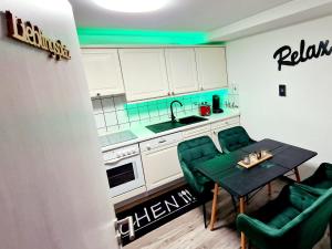eine kleine Küche mit einem Tisch und grünen Stühlen in der Unterkunft Mefady Ferienhaus Stadtkyll in Stadtkyll