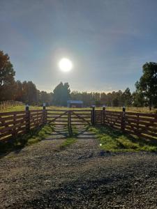 a fence on a field with the sun in the sky at Cordero in Osorno