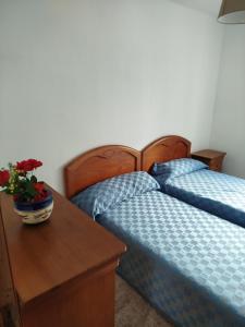 a bedroom with two beds and a table with a vase of flowers at Alojamiento en pleno centro de Castro Urdiales in Castro-Urdiales