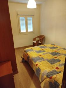 a bedroom with a bed and a chair and a window at Alojamiento en pleno centro de Castro Urdiales in Castro-Urdiales
