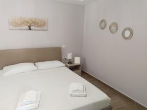 a bedroom with a white bed with towels on it at Io's Guest House in Ofrínion