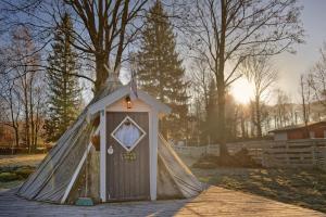 a teepee house with a door in a yard at Fińska Wioska Kalevala in Borowice