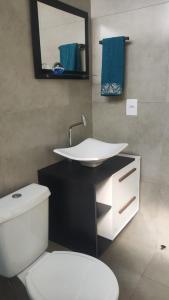 un bagno con lavandino, WC e specchio di Kitnet equipada pra descansar a Votuporanga