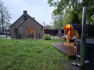 a house with a yard with chairs and a building at La casa Pacha Mama Sauna en Hottub in Ewijk