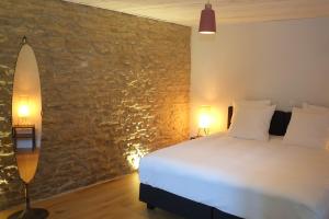 a bedroom with a bed and a stone wall at Au Petit Bercail - Le Loft - Gite pour 4 personnes in Chiny