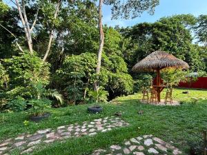 a table and chairs under a straw umbrella in a yard at Amasisa Casa Vacacional Sauce, Laguna Azul in Sauce