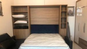 a bedroom with a bed and a closet with shelves at Glamz studio staycation Dubai in Sabkhah