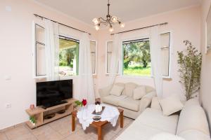a living room with a white couch and a tv at Eleonas Country House in Marantochori