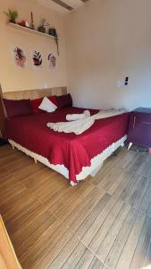 a bedroom with a large bed with a red blanket at Chalé Bella Serra piscina café da manhã incluso in Jaboticatubas