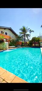 ein großer blauer Pool mit Palmen im Hintergrund in der Unterkunft Pousada Dolce Vita in Itanhaém