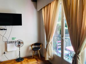 a room with a balcony with a television and a chair at BB Casita Blue Hotel in Santiago