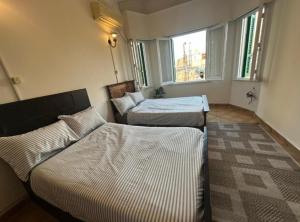 a room with two beds and a window at Agora House for men only 仅限男性 in Alexandria