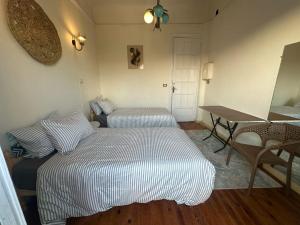 a bedroom with two beds and a table and a desk at Agora House for men only 仅限男性 in Alexandria