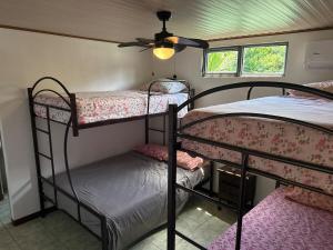 a room with two bunk beds and a ceiling fan at Playa Negra Zen Bistro in Puerto Limón