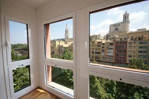 a room with three windows with a view of a city at Flateli Canalejas in Girona