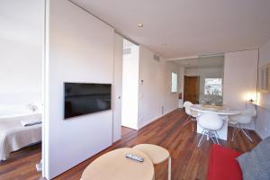 a living room with a television and a bed and a table at Flateli Canalejas in Girona