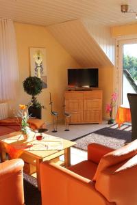 a living room with orange furniture and a television at Ferienwohnungen am Dreiländersee - zertifiziert - Annemarie Mantke in Haltepunkt Driland