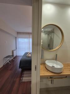 een badkamer met een wastafel en een spiegel en een bed bij Sleep Swell in Porto