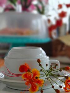 Una taza blanca y un platillo con flores sobre una mesa. en Pousada Casa da Praia Juquehy - Duplo, en Juquei
