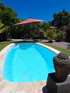 a swimming pool with an umbrella next to a house at Casita Tres Trapi in Noord