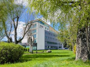 a large white building in a park with trees at Hotel Arman in Nižná