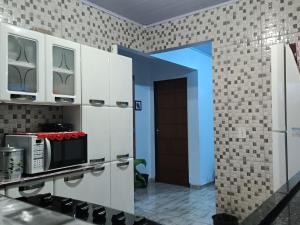 a kitchen with white cabinets and a microwave at Harmonia em sintonia in Alto Paraíso de Goiás