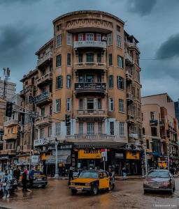 a yellow car parked in front of a tall building at Agora House for men only 仅限男性 in Alexandria