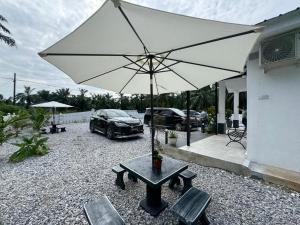 a table with an umbrella and two chairs and a car at Omah Kebun Private Pool in Sungai Besar