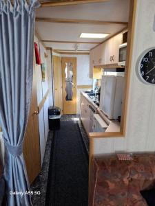 a small room with a kitchen and a clock on the wall at Mackies Memories. in Hemsby