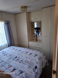 a bedroom with a bed with a comforter on it at Mackies Memories. in Hemsby