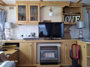 a living room with a television on a desk at Mackies Memories. in Hemsby