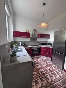 a kitchen with red cabinets and a sink and a refrigerator at Villa Léa Alès 5 chambres in Alès +19 photos