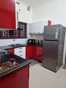 a kitchen with red cabinets and a stainless steel refrigerator at Short term 3 bedroom house in Chengannūr