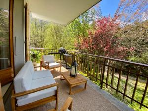 Un porche con un sofá blanco y sillas en un balcón. en Apartment Chamonix Brise du Mont, en Chamonix-Mont-Blanc