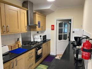 een keuken met houten kasten en een kookplaat met oven bij SAI Residence in Ilford +23 foto's