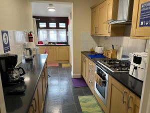 een keuken met houten kasten en een kookplaat met oven bij SAI Residence in Ilford