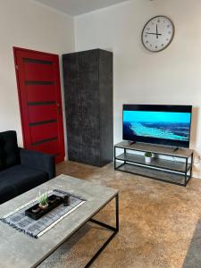 un soggiorno con divano, TV e sveglia di La Ville - Rouge a Zator Altre 5 foto