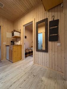 a room with wooden walls and a kitchen and a mirror at Brunella house at Villa Vlada in Gāršmuiža