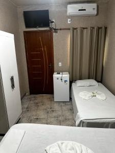 Canaã dos CarajásにあるHotel Carajás IIのベッドが2つと壁にテレビがある部屋