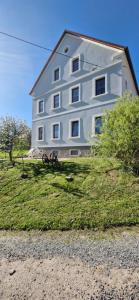 un grande edificio bianco, posto in cima a un prato di Ferienwohnung Schwalbennest a Großschirma