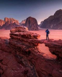 un hombre parado sobre una roca en el desierto en Desert calm, en Wadi Rum
