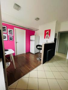 シャートラルヤウーイヘイにあるMalaika Apartmanのピンクの壁のリビングルーム(テーブル付)