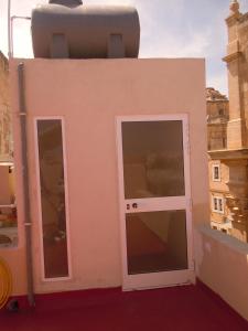 a small pink building with a door and windows at Number 12 in Birgu