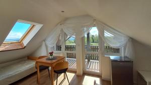 a attic room with a table and a balcony at Liść Klonu in Polańczyk