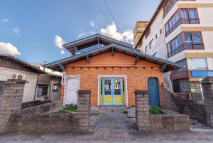 a small brick house with a blue and yellow door at Casa 5 Quartos no Centro para 14 Pessoas in Gramado
