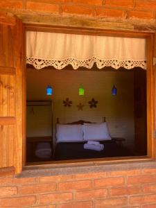 une fenêtre dans un bâtiment avec un lit dedans dans l'établissement Pousada Canto da Serra, à Conceição da Ibitipoca