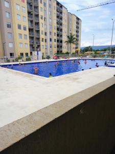 a large swimming pool with people in it with buildings at Confortable apartamento vacacional in Ricaurte +6 photos