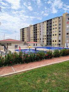 a swimming pool with flowers in front of a building at Confortable apartamento vacacional in Ricaurte