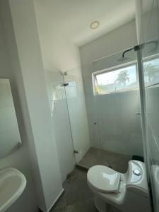 a white bathroom with a toilet and a shower at Mar, Hamaca, BBQ y Cocina, Hogar Entre Olas in Puerto Colombia +6 photos